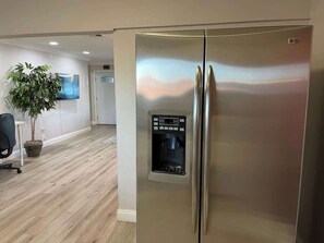 A stainless steel refrigerator with a water dispenser in a modern kitchen with wooden flooring and a potted plant. - Charming & Chic: Your Stylish Oasis for a Month-Long Retreat (Henderson)