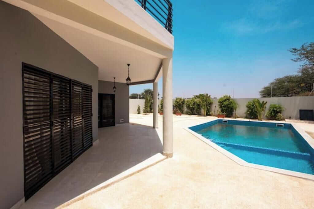 A modern house with a covered patio, a swimming pool, and a view of the surrounding area.