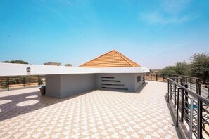 Une terrasse sur le toit avec un sol à motifs, un bâtiment doté d’un toit en pente et une rambarde.