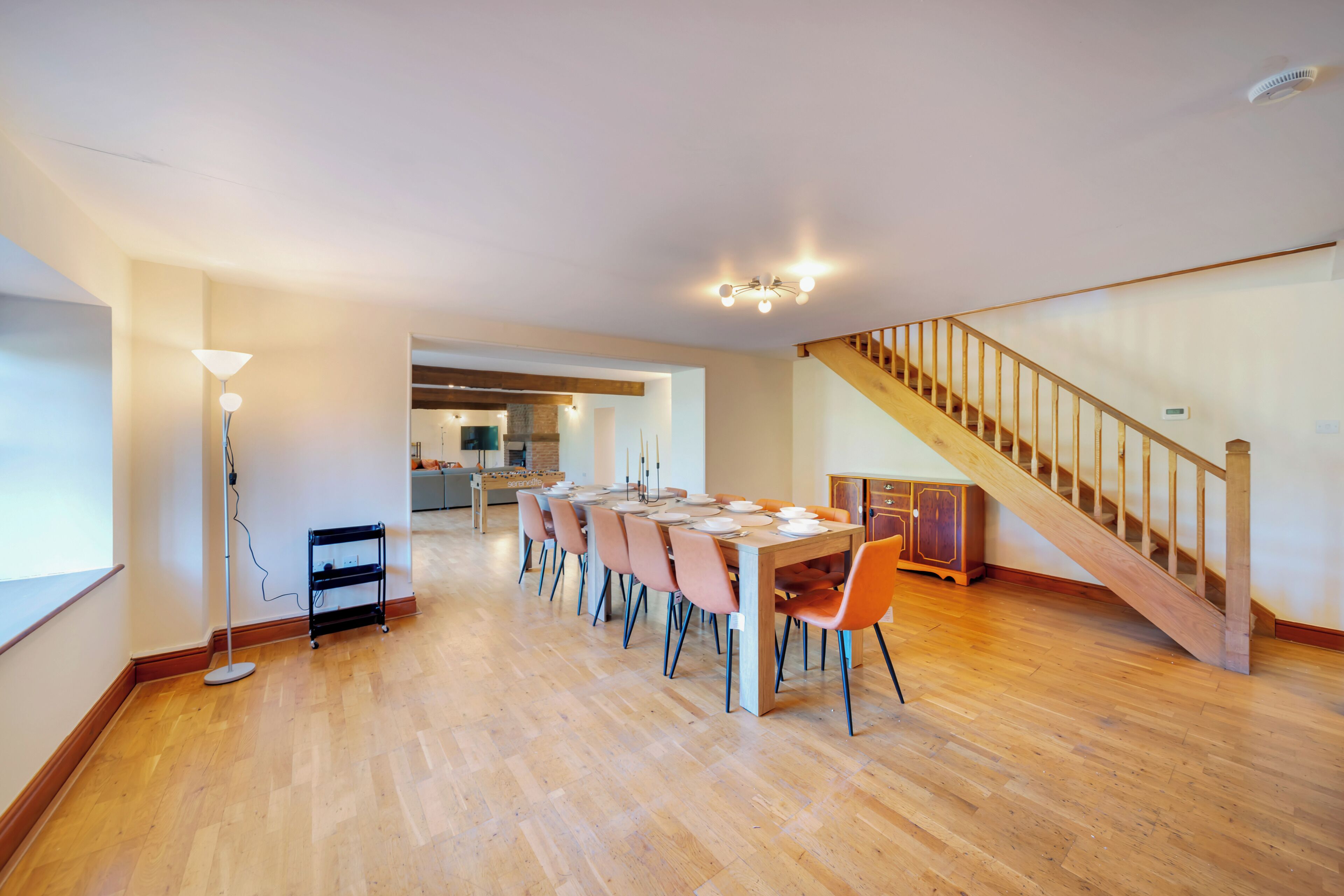 A spacious dining area with a long table, chairs, and a staircase.