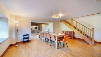 A spacious dining area with a long table, chairs, and a staircase.