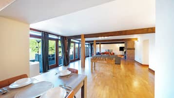 A spacious dining area with a long table set for a meal, a foosball table, and a view through large windows.