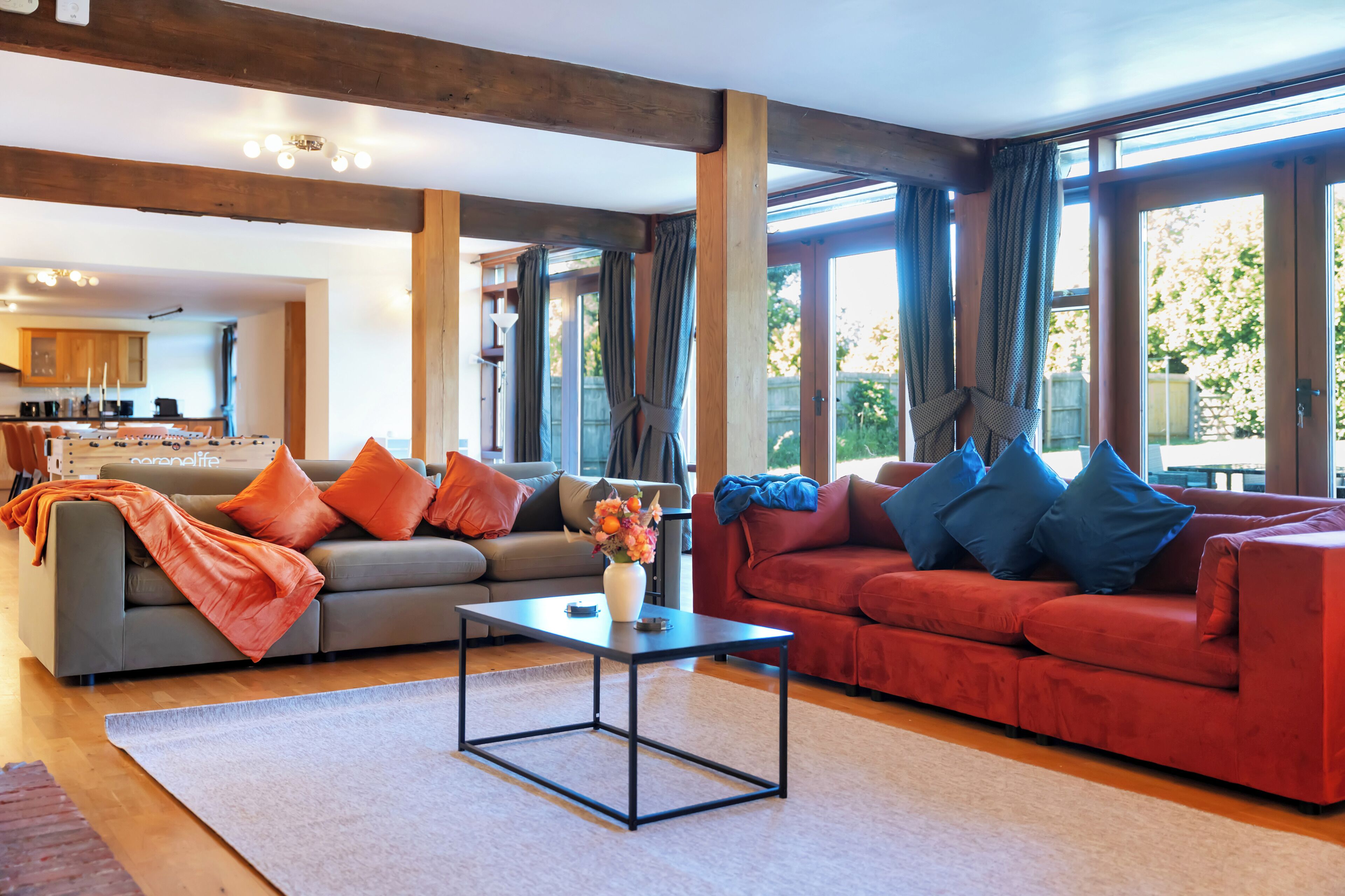 A spacious living area with a grey sofa, red sofa, and a coffee table.