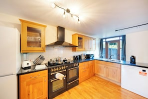Una cucina con mobili in legno, un fornello, forno e microonde.