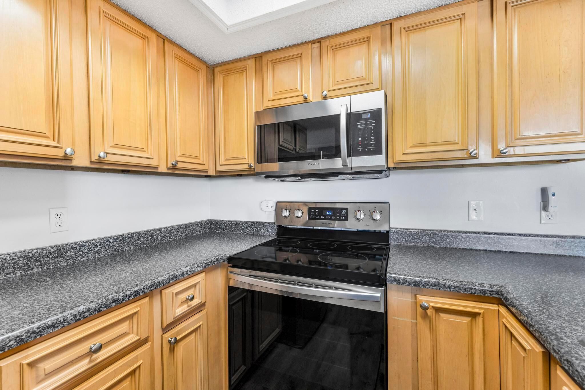 A kitchen with wooden cabinets, a stainless steel microwave, and a black stove.