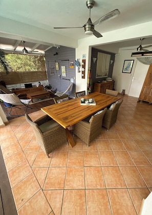 A dining area with a wooden table, wicker chairs, and a ceiling fan. - Villa Colibri - Private Pool - Panoramic View (Rivière-Salée)