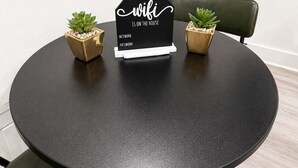 A round table with a black placemat, two small potted plants, and a black sign with white text. - Elegant Downtown Dallas Retreat (Dallas)