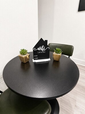 A round table with a black placemat, two small potted plants, and a black sign with white text. - Elegant Downtown Dallas Retreat (Dallas)