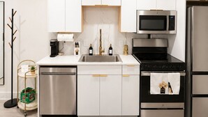 A modern kitchen with white cabinets, stainless steel appliances, and a black countertop. - Elegant Downtown Dallas Retreat (Dallas)