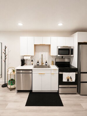 A modern kitchen with white cabinets, stainless steel appliances, and a black countertop. - Elegant Downtown Dallas Retreat (Dallas)