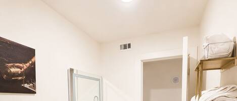 A modern bathroom with a white toilet, a vanity with a dark patterned sink, a mirror, and a towel rack.