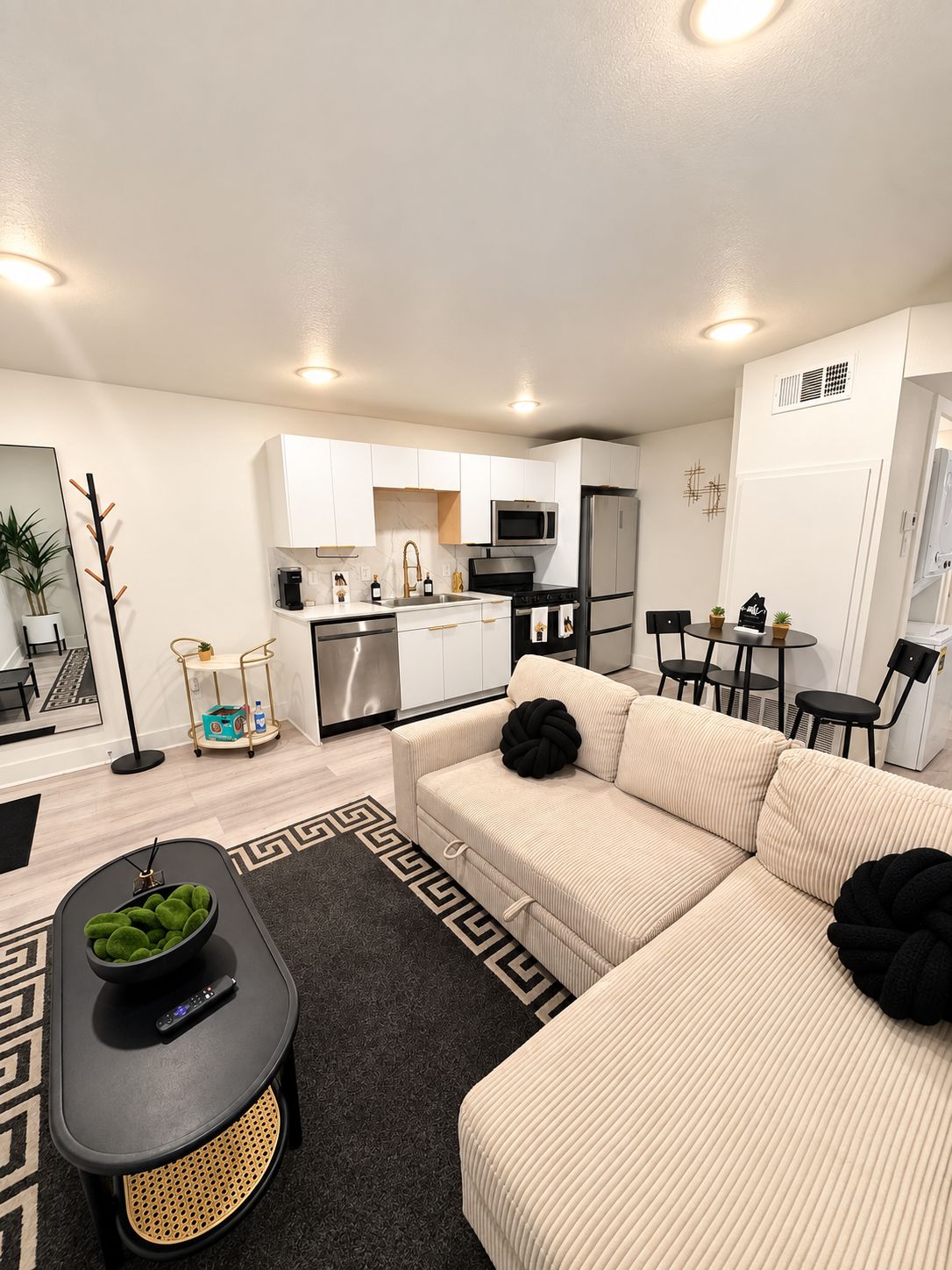 A modern apartment with a kitchenette, a sofa set, a dining area, and a small table with chairs.