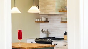 A kitchen with pendant lighting, a central island, and a red wine glass. - Historic 1915 Home · No Pet Fees (Chattanooga)