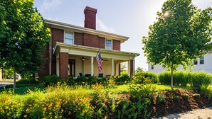 A two-story house with a brick facade, a front porch, and an American flag. - Historic 1915 Home · No Pet Fees (Chattanooga)