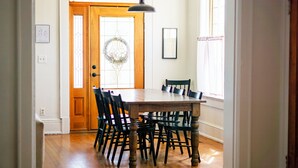 A dining room with a wooden table and chairs, a chandelier, and a door with a wreath. - Historic 1915 Home · No Pet Fees (Chattanooga)