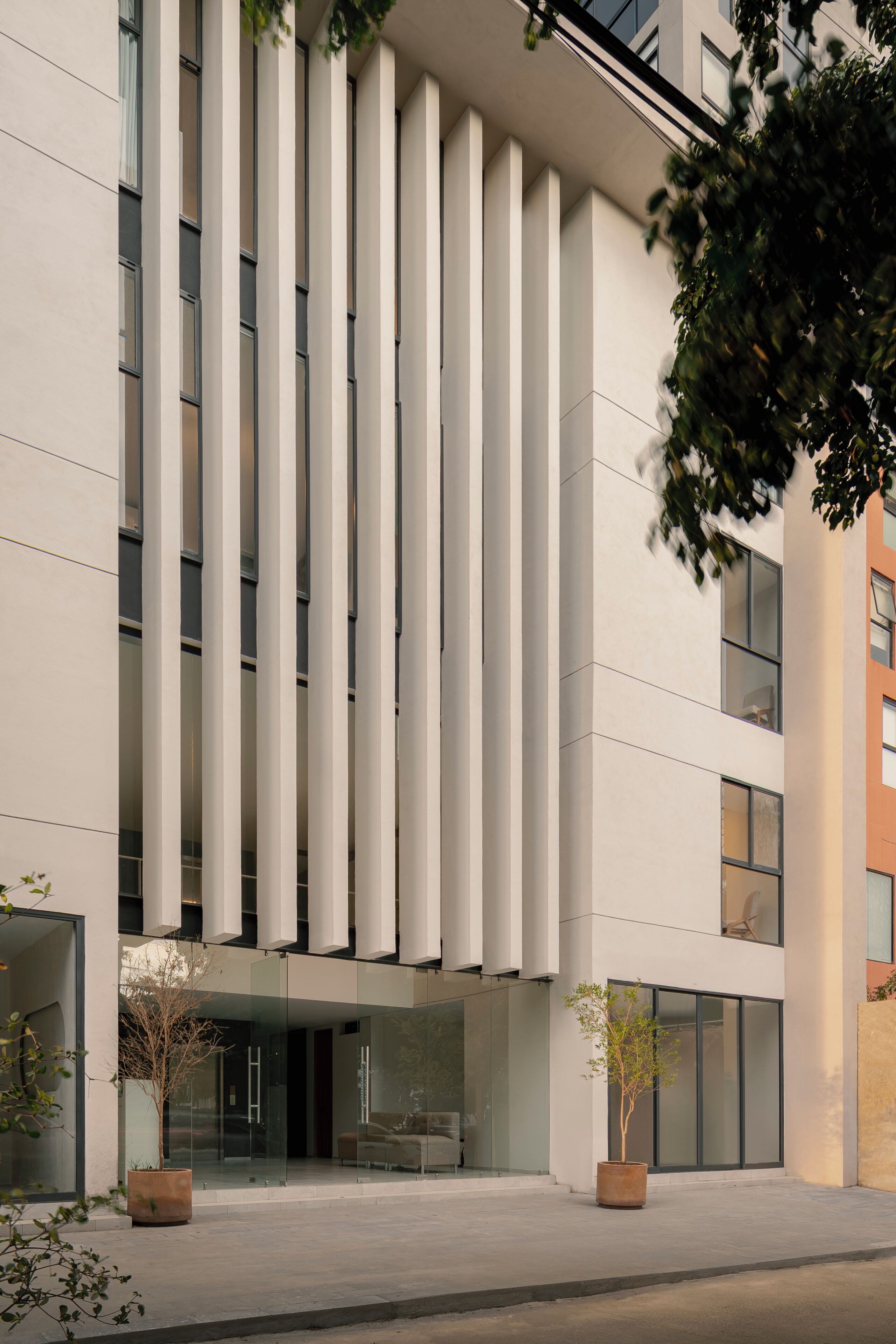 A modern building with vertical lines, large windows, and potted plants.