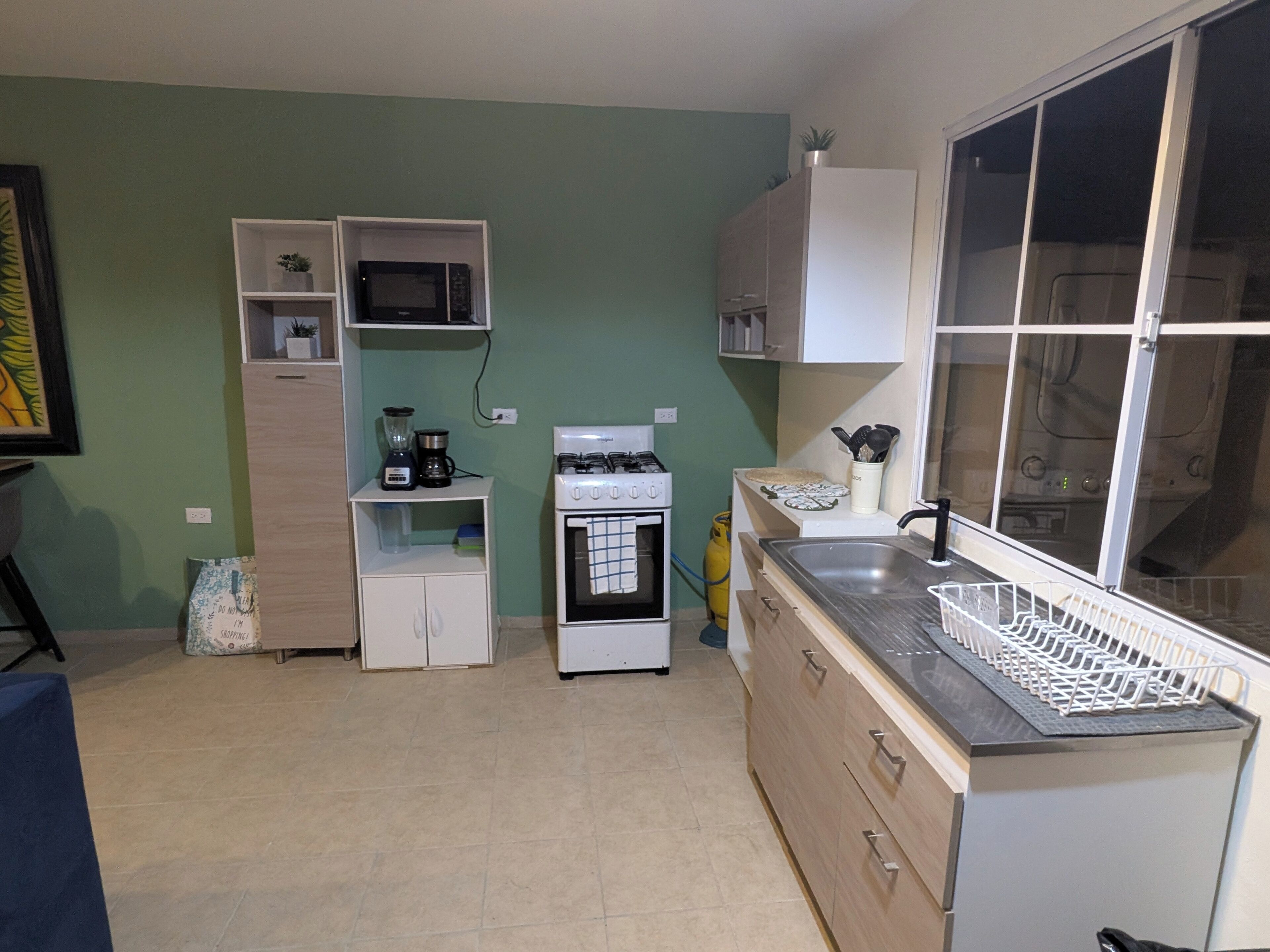 A compact kitchen with a stove, microwave, and white cabinets.