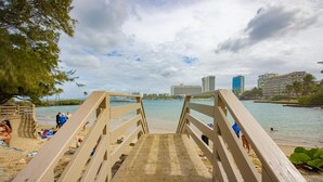 A wooden staircase leading to a beach with a view of the ocean and buildings in the background. - Cute Apartment for Couples in San Juan (San Juan)