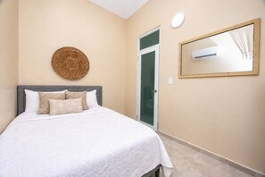 A hotel room with a bed, a round wall decoration, a door, and a mirror. - Cozy 2 Br Apartment Steps from La Cerra (San Juan)
