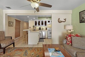 Ein Wohnzimmer mit einer Couch, einem Couchtisch, einem gemusterten Teppich und einem Deckenventilator.