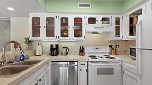 A kitchen with white cabinets, stainless steel appliances, and a green wall. - Ocean View Condo with Lanai, Pools in Kailua-Kona (Kailua Kona)