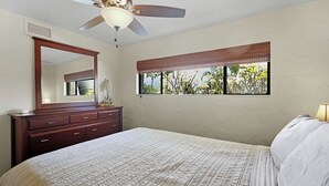 A bedroom with a bed, a ceiling fan, a window with a view, and a dresser. - Ocean View Condo with Lanai, Pools in Kailua-Kona (Kailua Kona)