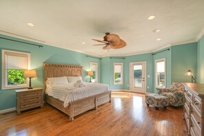 Ein Schlafzimmer mit einem hölzernen Bett, einem Deckenventilator und Blick ins Freie.