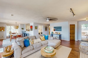 A spacious living room with a large sofa, a dining area, and a kitchen visible in the background. - Another Tequila Sunrise - Lakefront Condo W/breathtaking Views & Wheelchair Accessibility (Moneta)