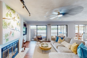 A living room with a fireplace, a sofa, a coffee table, a chair, and a view of the outdoors. - Another Tequila Sunrise - Lakefront Condo W/breathtaking Views & Wheelchair Accessibility (Moneta)