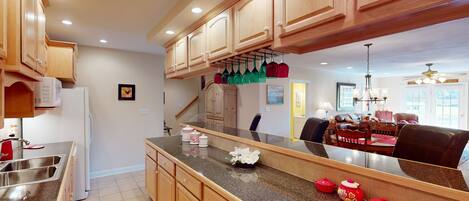A kitchen with wooden cabinets, a granite countertop, and a dining area with a chandelier.