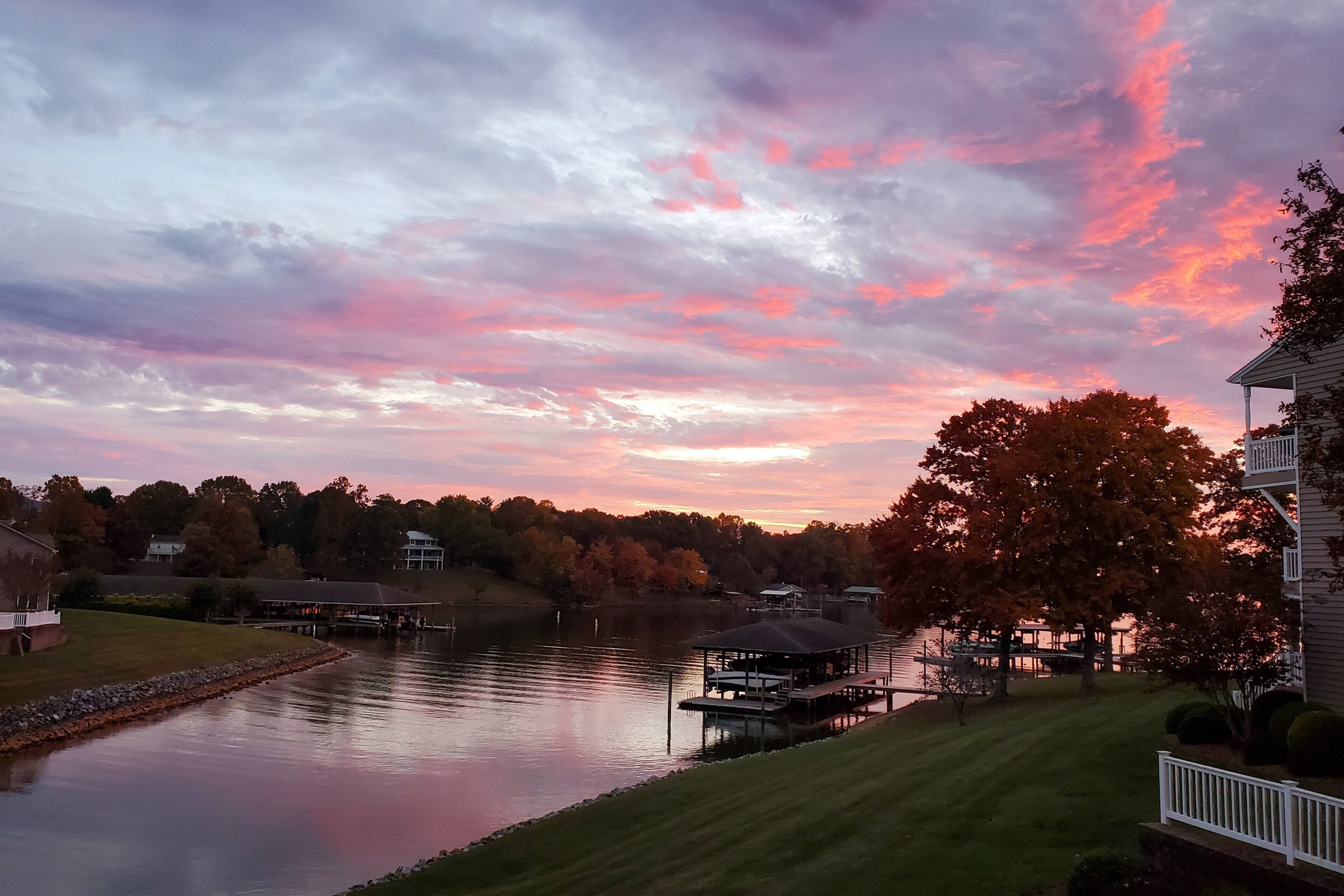 A lakeside view with a gazebo, dock, and houses.