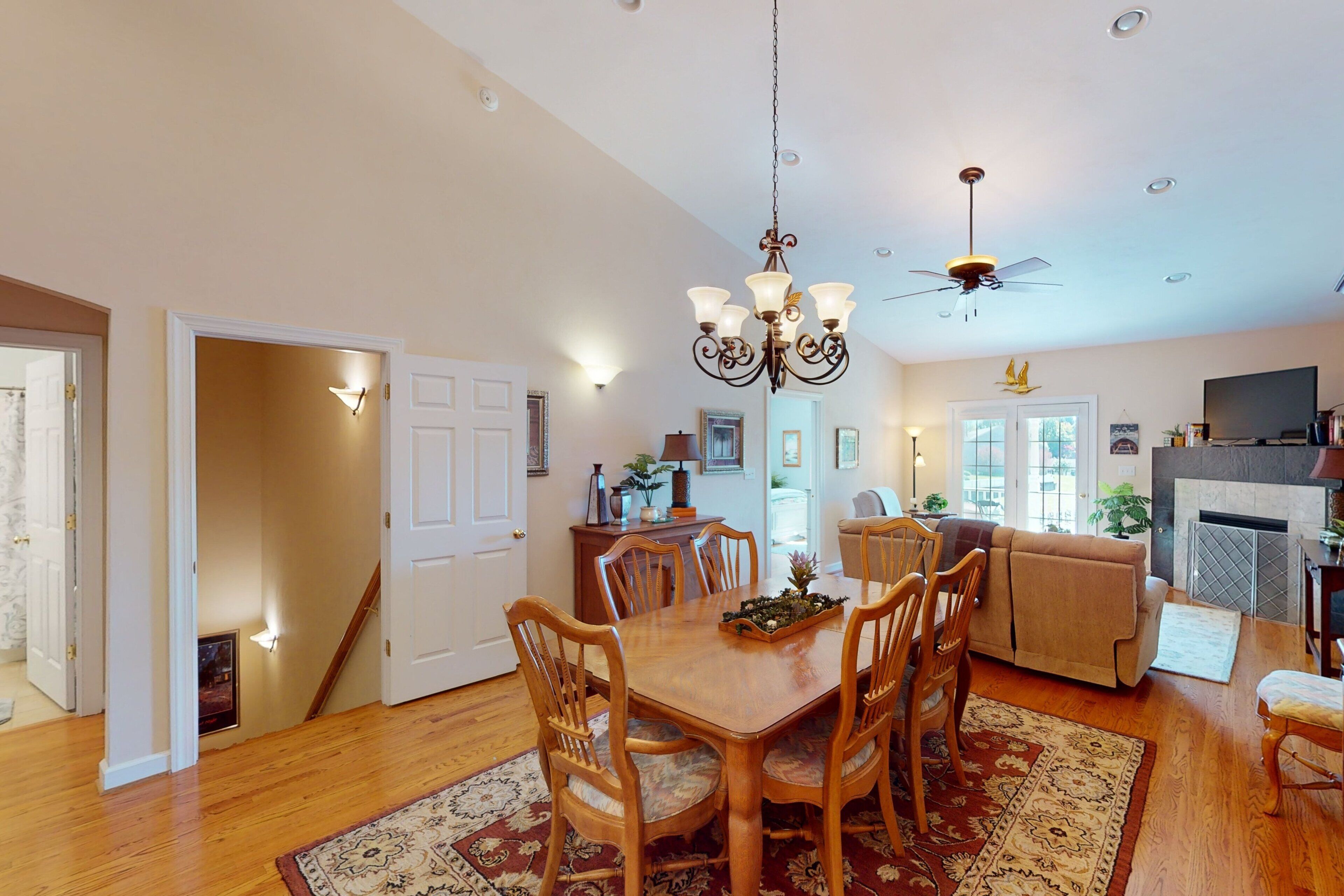 A dining area with a wooden table and chairs, a chandelier, and a fireplace.