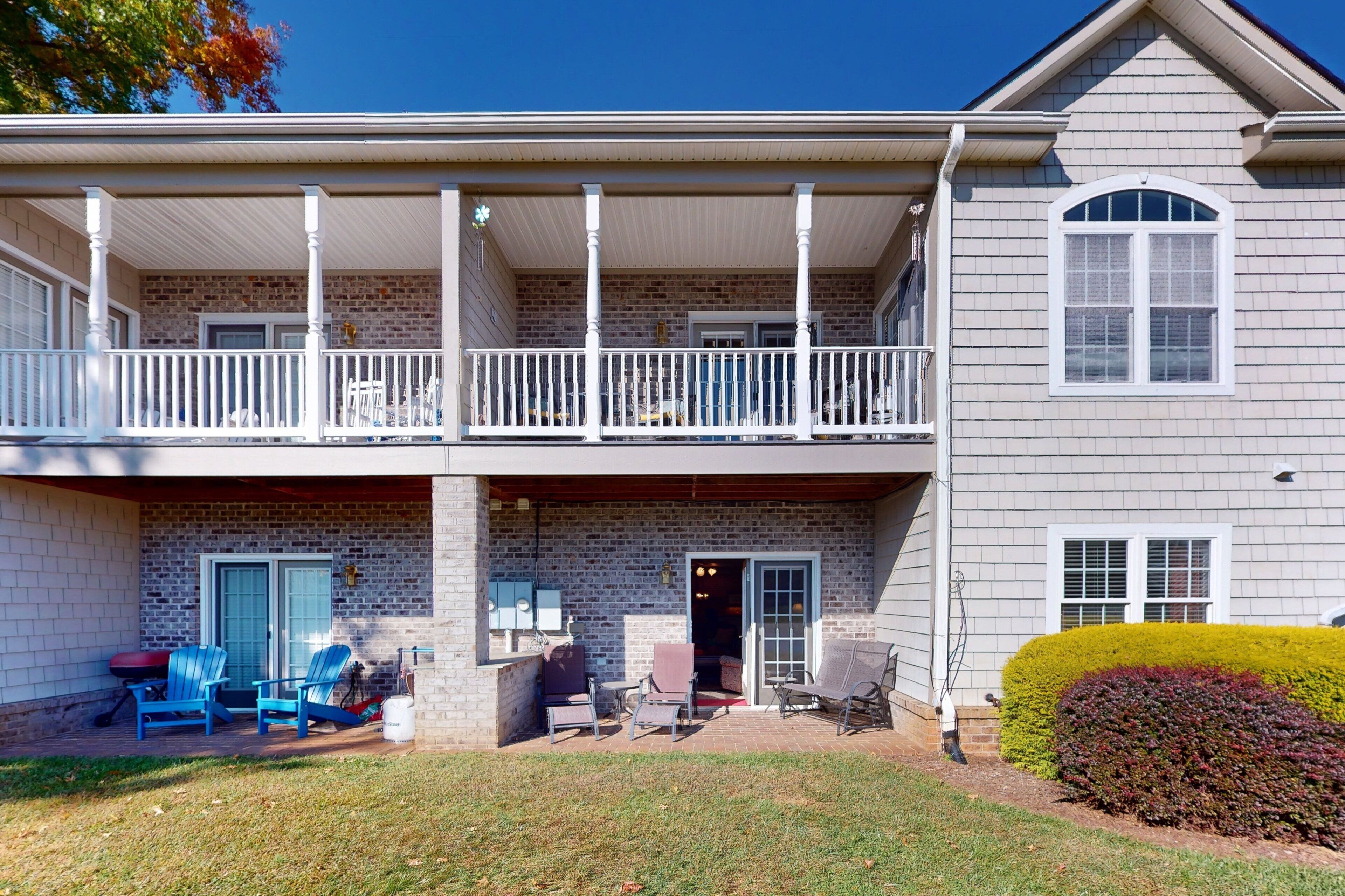 A two-story house with a covered patio, brick exterior, and a small garden.