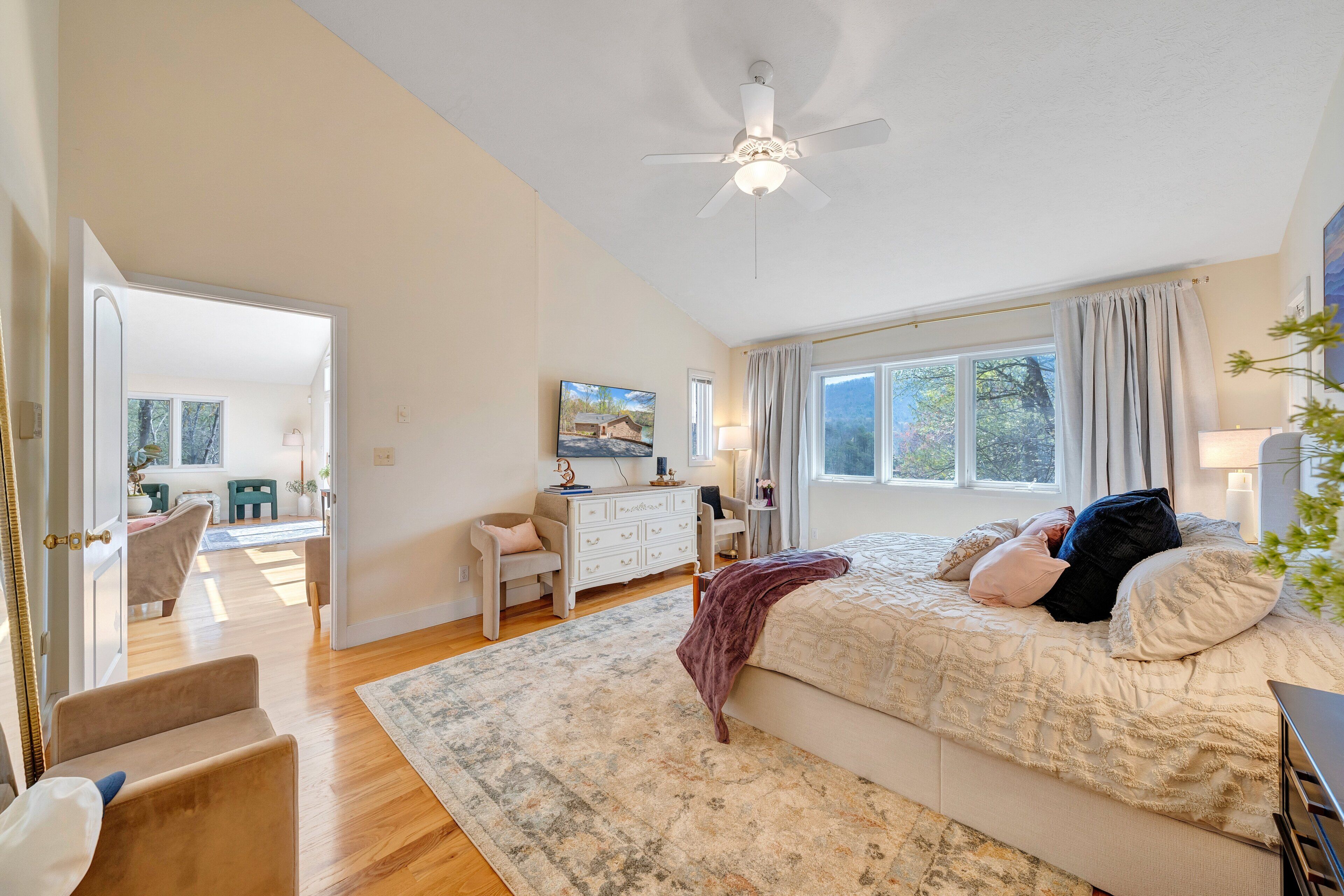 Une chambre à coucher comprenant un lit, un bureau, une chaise, une commode et un ventilateur de plafond.