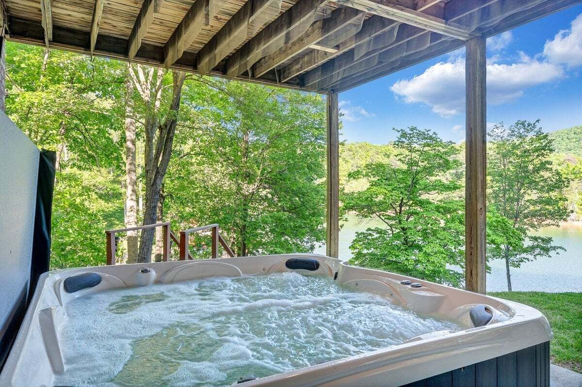 A hot tub with a view of a lake and trees.