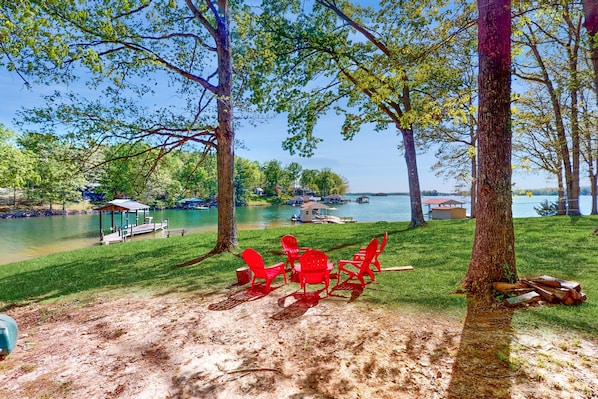 A lakeside setting with red chairs, a gazebo, and a dock. - Jewelbox Cottage - Dog-friendly Lakefront Home With Private Dock, Canoe & Sups (Huddleston)