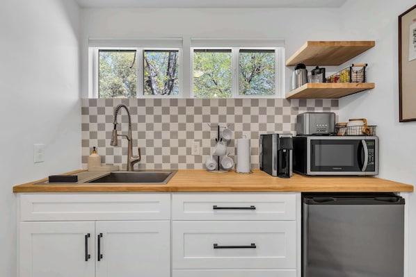 A kitchen with a sink, two windows, a microwave, and a dishwasher.