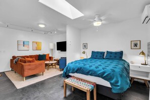 A modern bedroom with a bed, a sofa, a desk, and a bench.