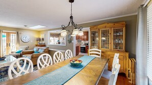 A dining area with a wooden table, chairs, and a chandelier. - Smith Mountain Bliss - Spacious Waterfront House W/patio, Deck, Fire pit & Grill (Moneta)