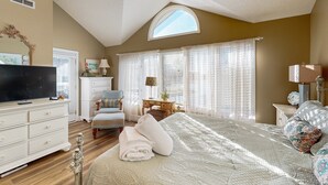 A bedroom with a large bed, a television, a dresser, a chair, and a desk with a lamp. - Smith Mountain Bliss - Spacious Waterfront House W/patio, Deck, Fire pit & Grill (Moneta)