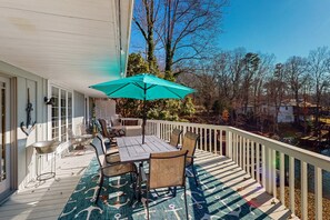 A covered outdoor deck with a table and chairs, a teal umbrella, and a patterned rug. - Smith Mountain Bliss - Spacious Waterfront House W/patio, Deck, Fire pit & Grill (Moneta)