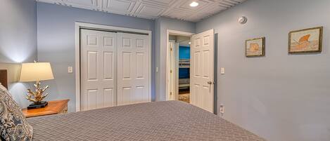 A bedroom with a bed, a nightstand, a lamp, and a door leading to a closet.