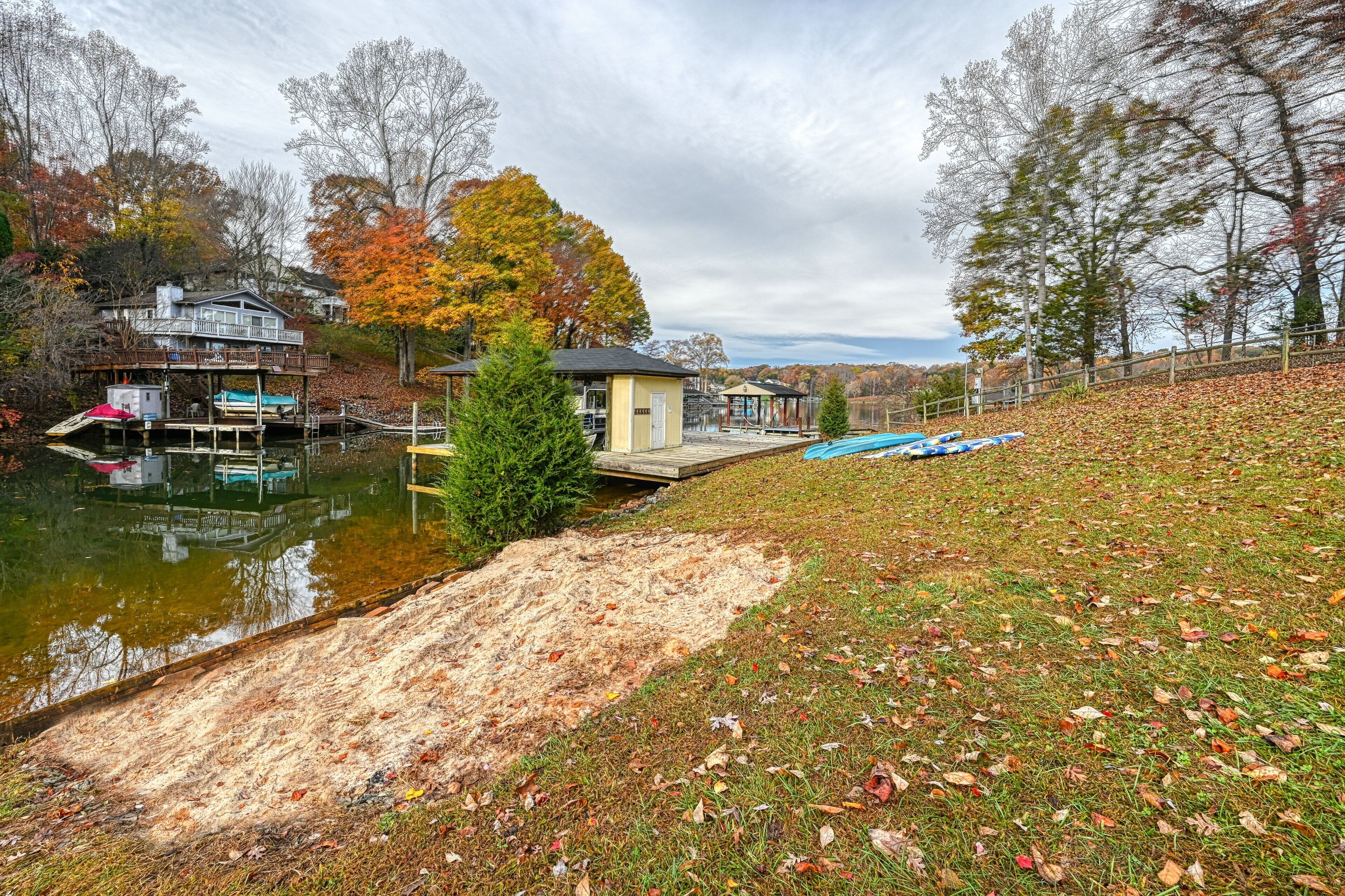 Une propriété au bord du lac, dotée d’un quai, d’un petit chalet et d’une zone herbeuse parsemée de feuilles mortes.