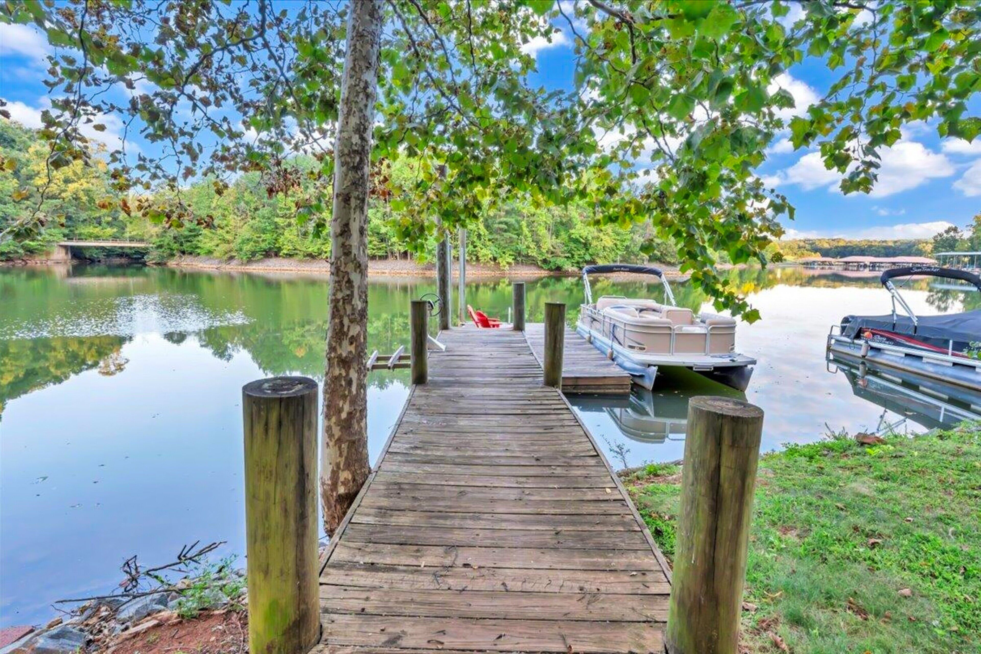 A wooden dock extending into a calm body of water, with boats docked on the right.