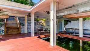 Eine überdachte Außenterrasse mit Pool, Holzstufen und einer überdachten Sitzgruppe.