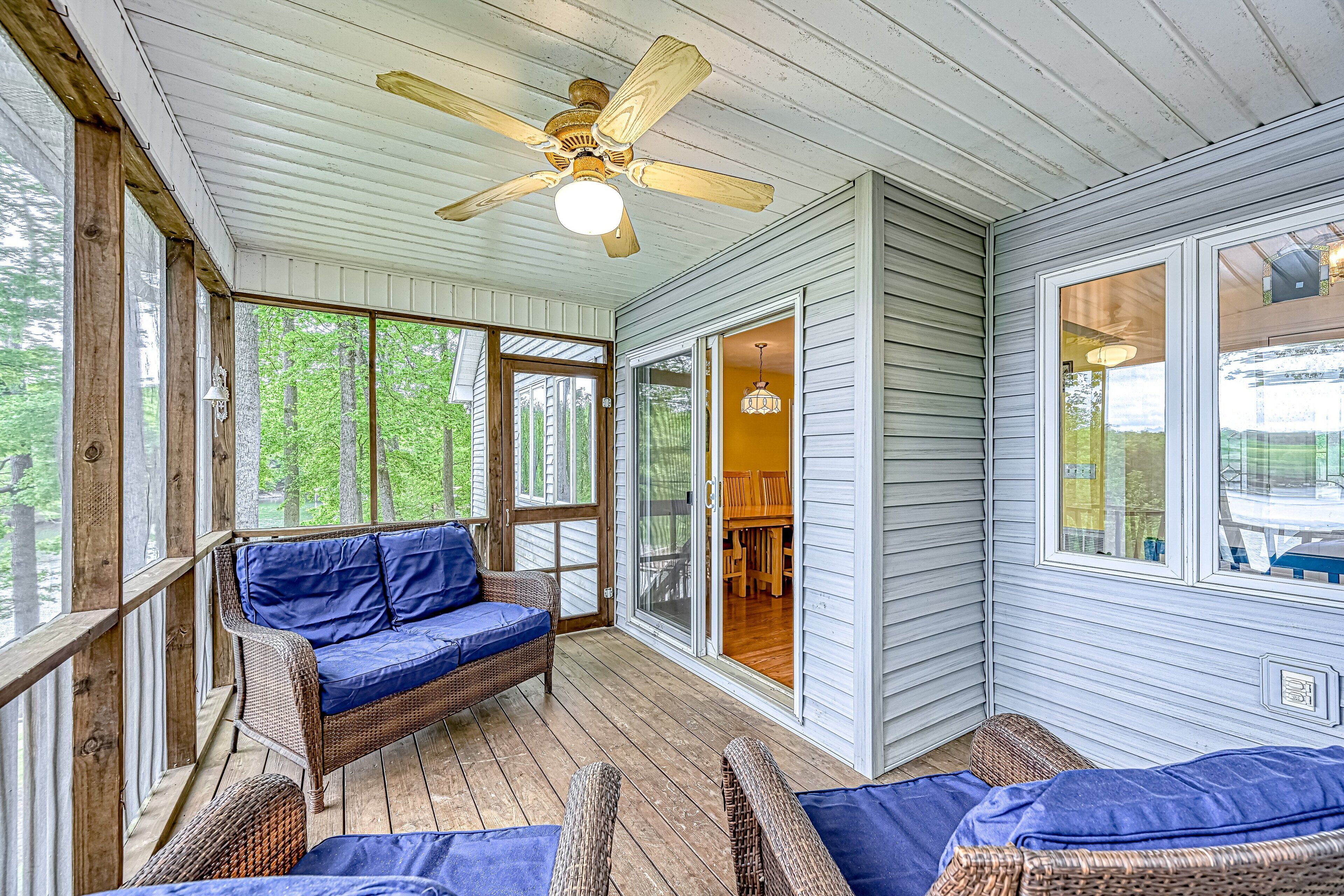 A covered porch with a ceiling fan, wicker furniture, and a view of the outdoors.