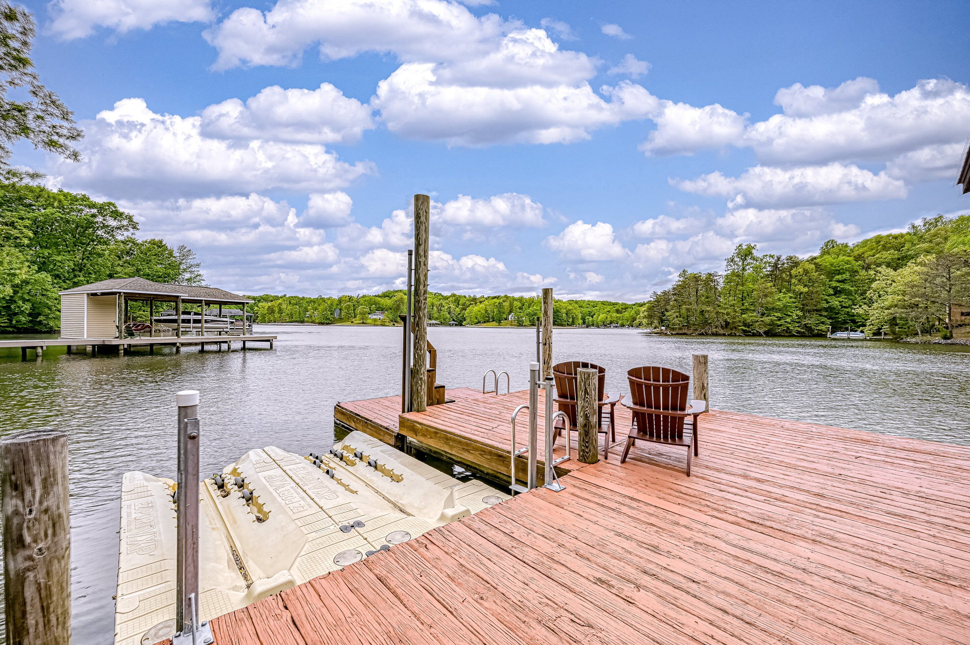 A wooden dock with a covered seating area, a boat launch ramp, and a chair.