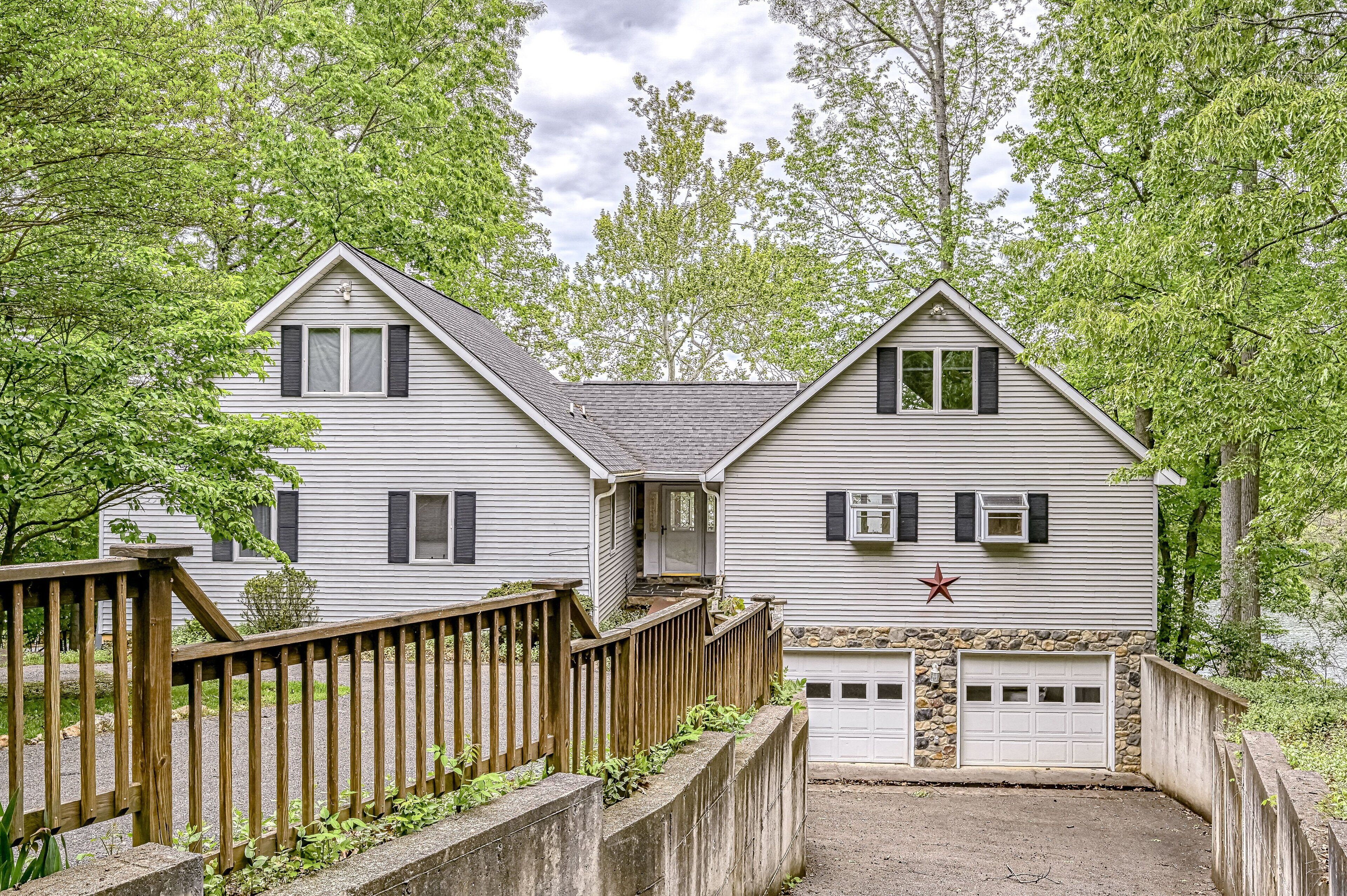 A two-story house with a stone foundation garage, a wooden deck, and a red star decoration.