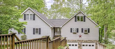 A two-story house with a stone foundation garage, a wooden deck, and a red star decoration.