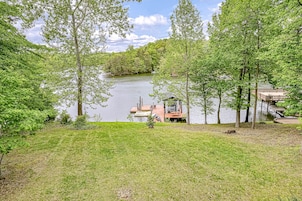 A lakeside property with a dock, a small cabin, and surrounding greenery.